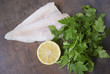 Frozen Alaska Pollock fillet with lemon and parsley. Preparation for cooking.