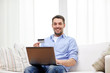© Syda Productions - smiling man with laptop and credit card at home