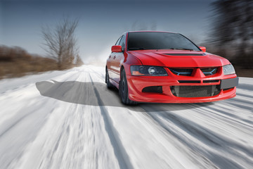 Red sport car driving speed on road at winter daytime