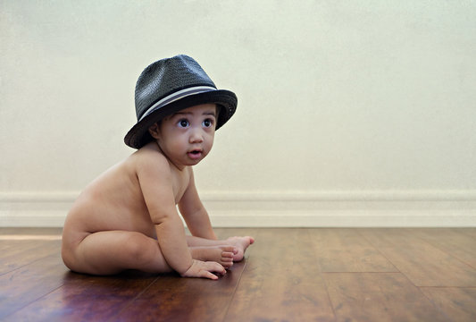Baby With Hat / Infant sitting nude baby with a confused look and wearing a hat.