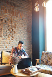 Fototapeta Na drzwi - Young man sitting at a cafe, using a laptop