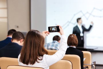 Businesswoman making video with mobile phone on business conference