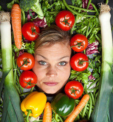 Cute blond girl shot in studio with vegetables aroound the head