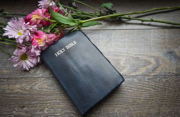 Christian Easter Holiday Background.  Bouquet of spring flowers frame a King James Bible. Shot from above on a rustic wood background.