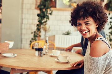 Cheerful young woman at a cafe with friends