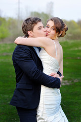 Wall Mural - loving bride and groom walking in summer nature