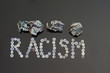 Racism spelled out with buttons.  Crumpled up money on top.