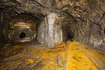 Old abandoned iron mine tunnel passage with broken wall and soviet union star logo