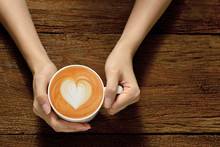 Woman Holding Cup Of Coffee Latte, With Heart Shape

