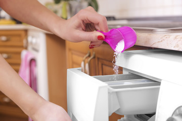 Wall Mural - Woman throws laundry detergent into the washing machine.