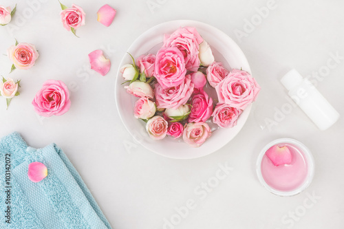 Plakat Ustawienia uzdrowiskowe z róż. Świeże róże i płatki róż w misce z wodą i różne przedmioty używane w zabiegach spa