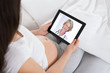 Expecting Woman Talking To Doctor On Digital Tablet