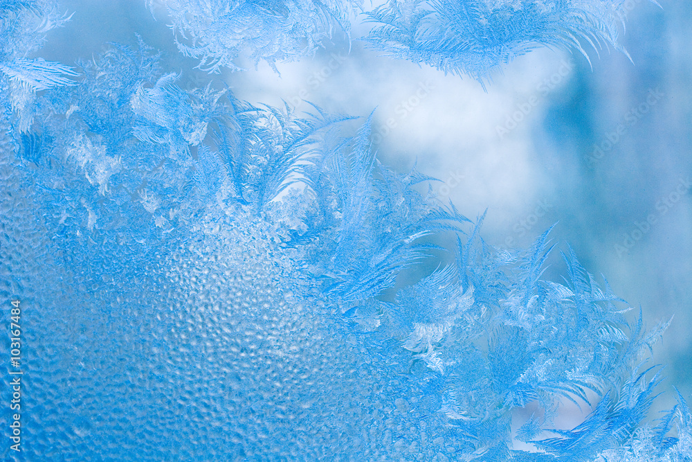 Slightly blurred beautiful frost pattern and drops of water on a window ...