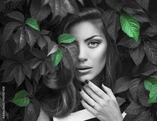 Naklejka na meble Sexy Beauty Girl with coral Lips. Provocative green Make up. Luxury Woman with Green Eyes. Fashion Brunette Portrait in wild leaves (grapes), natural background. Gorgeous Woman Face. Long Hair