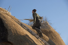 Thatcher Walking On A Ladder With Hazel Wood Spars To Form The Ridge Of A Thatched Roof