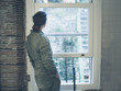 © LoloStock - Woman in boiler suit looking out the window