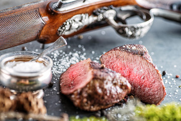 deer or venison steak with antique long gun and ingredients like sea salt and pepper, food backgroun