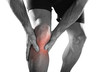 young sport man with athletic legs holding knee with hands in pain after suffering injury running