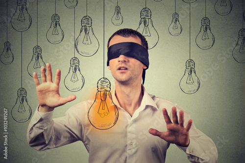 Fotografía Blindfolded young man walking through light bulbs searching for bright idea