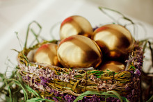 Golden Easter Eggs In Nest On White Wooden Background