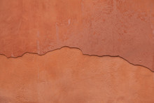 Old Terracotta Painted Stucco Wall With Cracked Plaster. Backgro