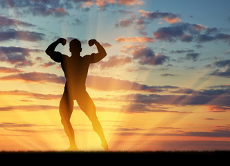 Silhouette of bodybuilder poses at sunset