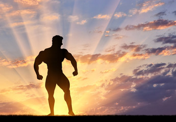 Silhouette of bodybuilder poses at sunset