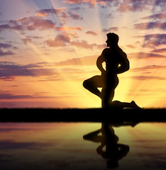 Silhouette of bodybuilder posing at sunset
