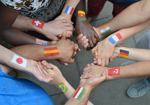 internationale brüder und schwestern mit unterschiedlichen flaggen auf ihren armen gemalt stehen mit