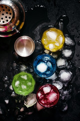 Blue, red, yellow and green cocktails with ice on a dark backgro