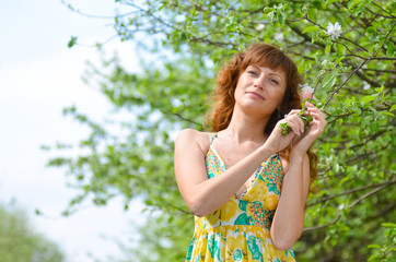 Wall Mural - young beautiful girl walks in the spring green apple orchard