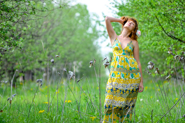 Wall Mural - young beautiful girl walks in the spring green apple orchard