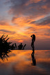 Silhouette of slim woman standing on infinity luxury pool