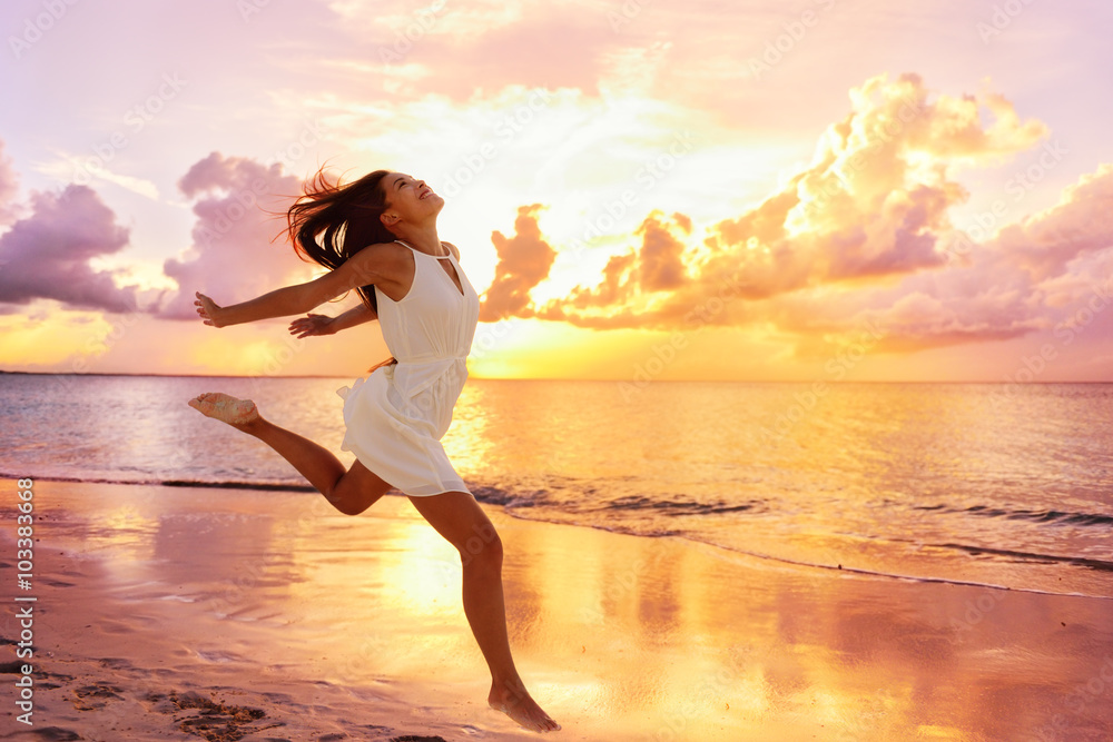 Freedom wellness well-being happiness concept. Happy carefree Asian woman feeling blissful jumping of joy on peaceful beach at sunset. Serenity, relaxation, mindfulness, stress free concepts. - obrazy, fototapety, plakaty 