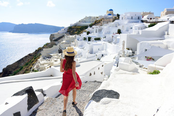 Wall Mural - santorini travel tourist woman on vacation in oia walking on stairs. person in red dress visiting th