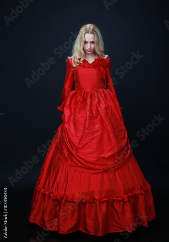 Foto full length portrait of a beautiful blonde woman wearing a historical red silk, victorian era ball gown