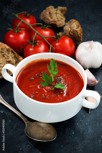 Fototapeta na wymiar tomato cream soup on a dark background, vertical