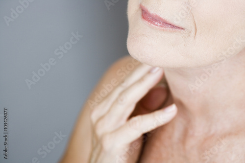 Foto  A senior woman touching her neck