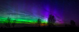 Panoramic photo of green and purple Aurora Borealis in Estonia
