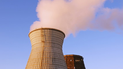 Wall Mural - Water cooling tower stack smoke over blue sky background. Energy generation and air environment pollution industrial scene. 4K UHD video footage.