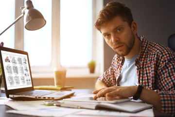 Canvas Print - Enjoying good working day. Confident young man working on laptop while sitting at his working place 