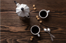 Two Cups Of Espresso With Pieces Of Cane Sugar And Italian  Coffee Maker On Wooden Table.