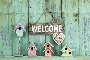 Wall Mural - Welcome sign with heart hanging over colorful birdhouses