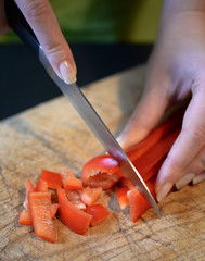  Female slicing pepper for salad. Close up chef cutting vegetabl