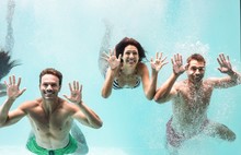Two Couples Swimming Underwater In Swimming Pool