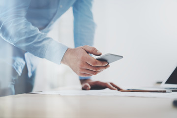 Photo of generic design smart phone holding in businessman hands. Blurred background. Horizontal mockup