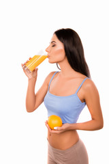 Poster - Slim young woman drinking orange juice and holding orange