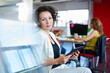 © AYAimages - Confident female designer working on a digital tablet in red creative office space