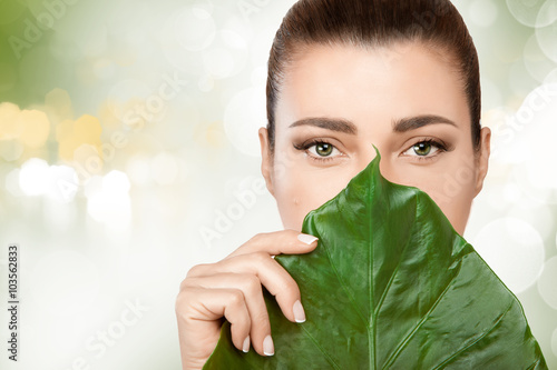 Fotografie, Obraz Gorgeous young woman with a fresh leaf to her face