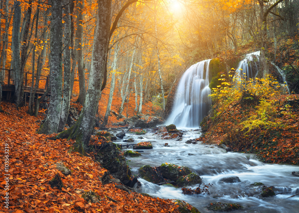 Beautiful waterfall at mountain river in colorful autumn forest
